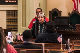 Annette Reed, dean of Sacramento State's new Native American College, speaks into a microphone.