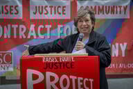 AFT president Randi Weingarten speaks in May 2024 in front of a  sign that says Raises Justice Community