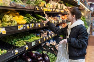A woman shops for produce at a grocery store.