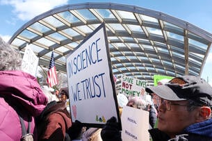 Protesters hold signs outside of the National Institutes of Health.