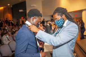 Calvin Hadley adjusts a student's tie at the You Lead tie ceremony.